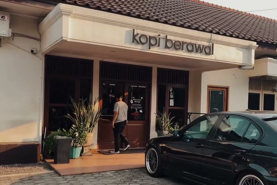 Fasad Kopi Berawal: rumah putih beratap genteng dengan papan nama kopi berawal di atas teras